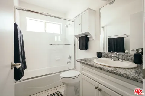 a bathroom with a granite countertop sink toilet and shower