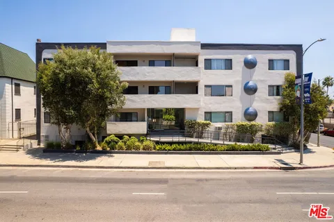 a front view of a building with a garden and plants