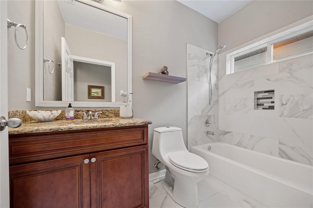 8267 Southwest 78th Lane Gainesville, FL 32608 - Photo 19 of 57 a bathroom with a granite countertop toilet sink and mirror