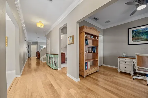 a view of a hallway with workspace and bedroom with windows