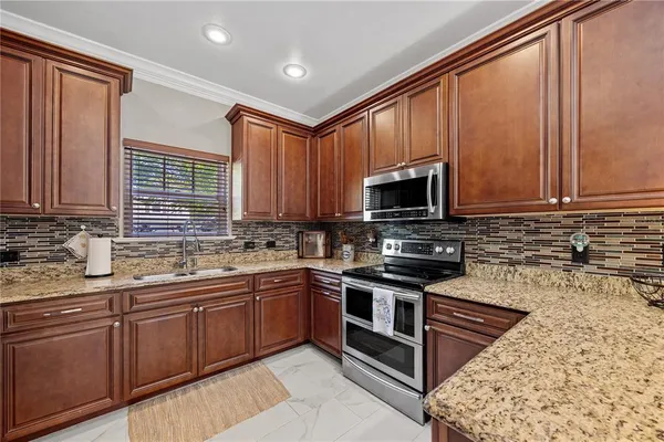 a kitchen with stainless steel appliances granite countertop wooden cabinets a sink and a stove