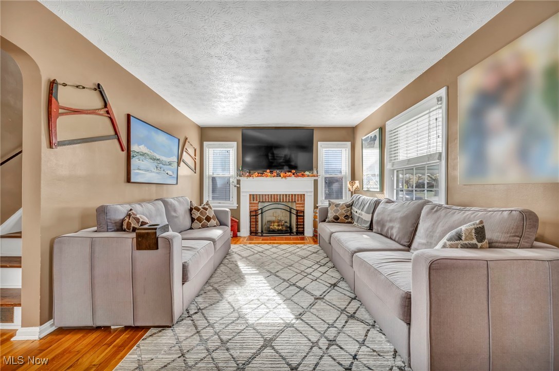 1645 Lander Road Cleveland, OH 44124 - Photo 11 of 38 Living room featuring hardwood / wood-style floors, a textured ceiling, and a brick fireplace