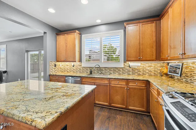 a kitchen with kitchen island granite countertop a sink stove and cabinets