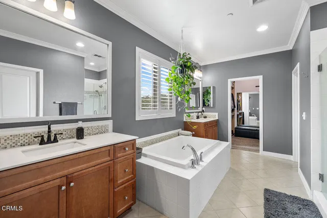 a en suite bathroom with a double vanity sink tub and mirror