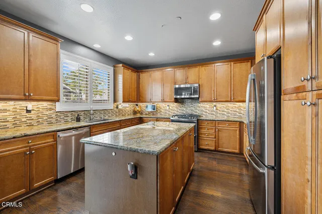 a kitchen with kitchen island granite countertop stainless steel appliances a sink stove and refrigerator