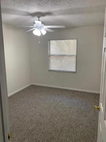an empty room with a chandelier fan and windows