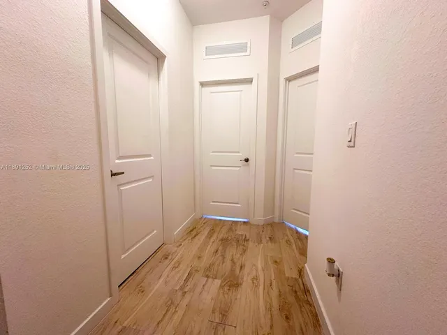 a view of a room with wooden floor and a bathroom