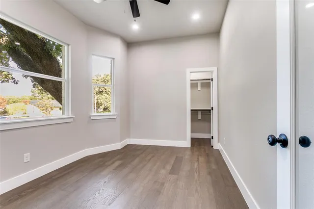 an empty room with windows and ceiling fan