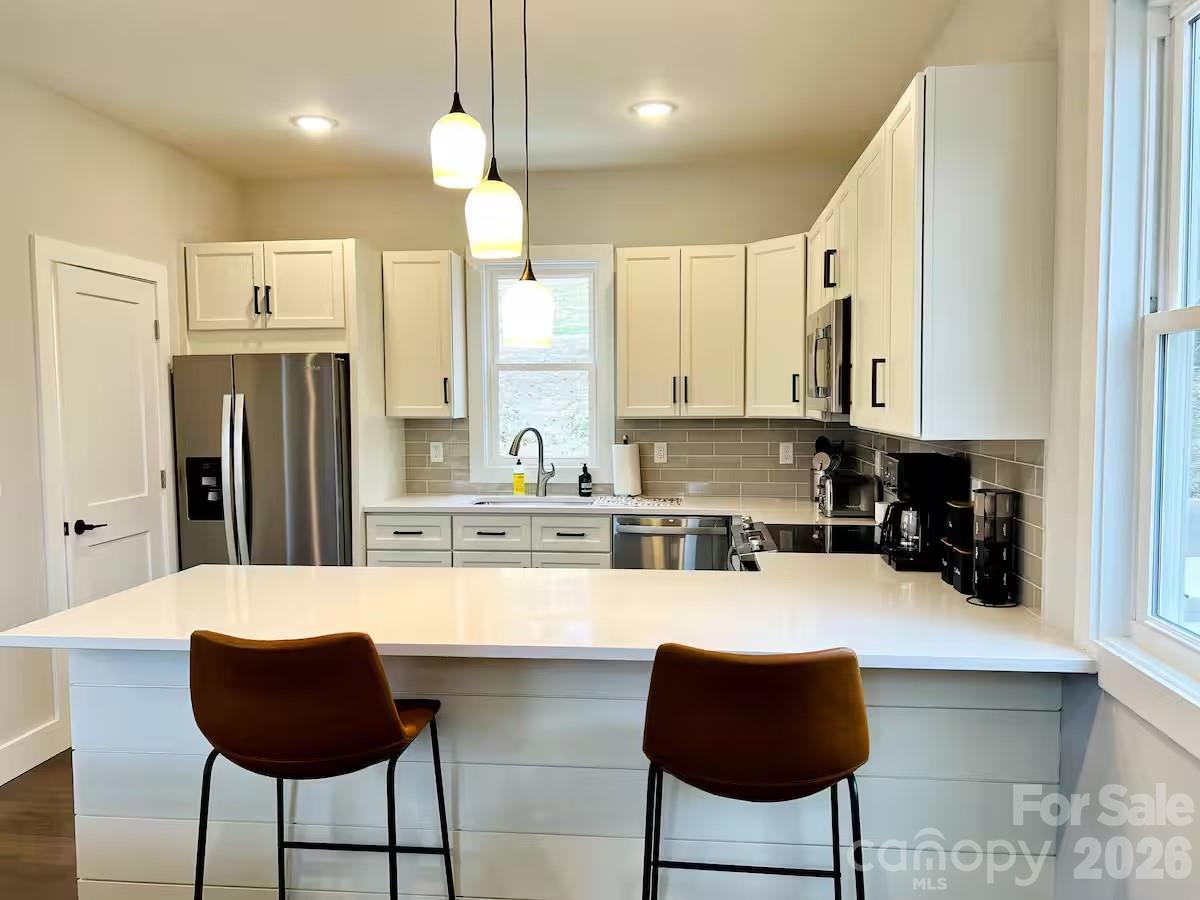 1063 Riverside Drive Asheville, NC 28804 - Photo 6 of 40 a kitchen with stainless steel appliances kitchen island granite countertop a refrigerator and a stove top oven with white cabinets