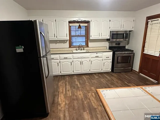 a kitchen with granite countertop a refrigerator stove and sink