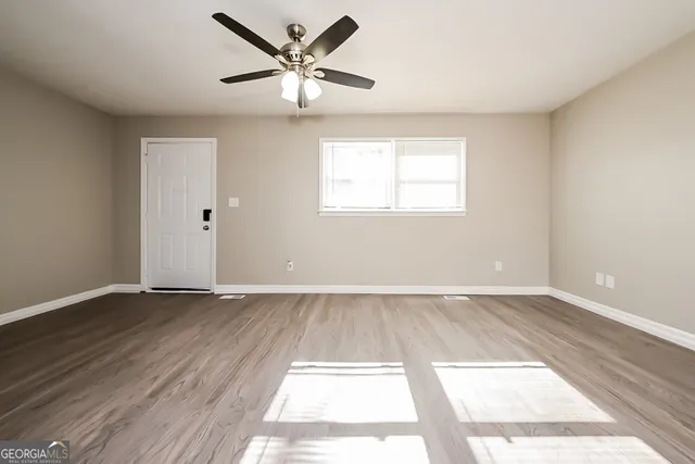 an empty room with wooden floor and windows