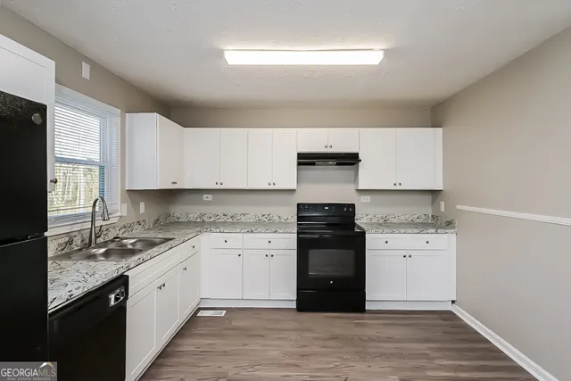 a kitchen with granite countertop a sink and a stove top oven