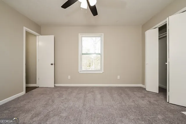 a view of an empty room with window and closet area