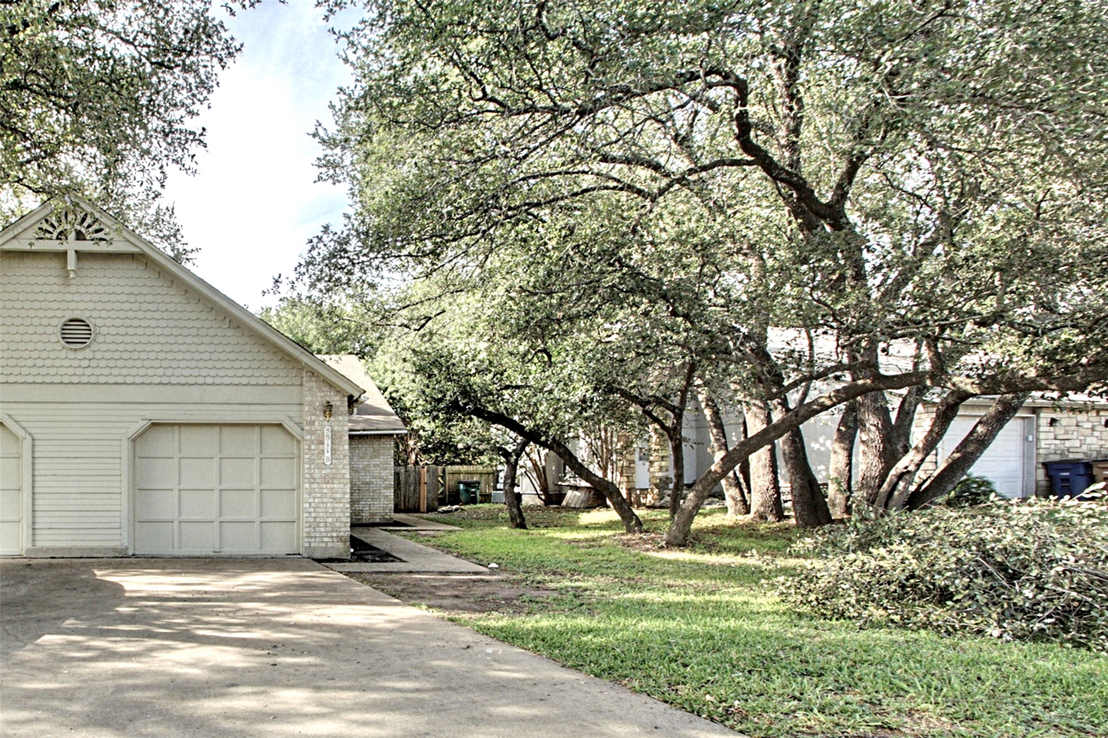 8811 Clearbrook Trail Austin, TX 78729 - Photo 34 of 38 rt B - Mature trees shade this charming residence featuring a prominent garage and driveway, enhancing its curb appeal.