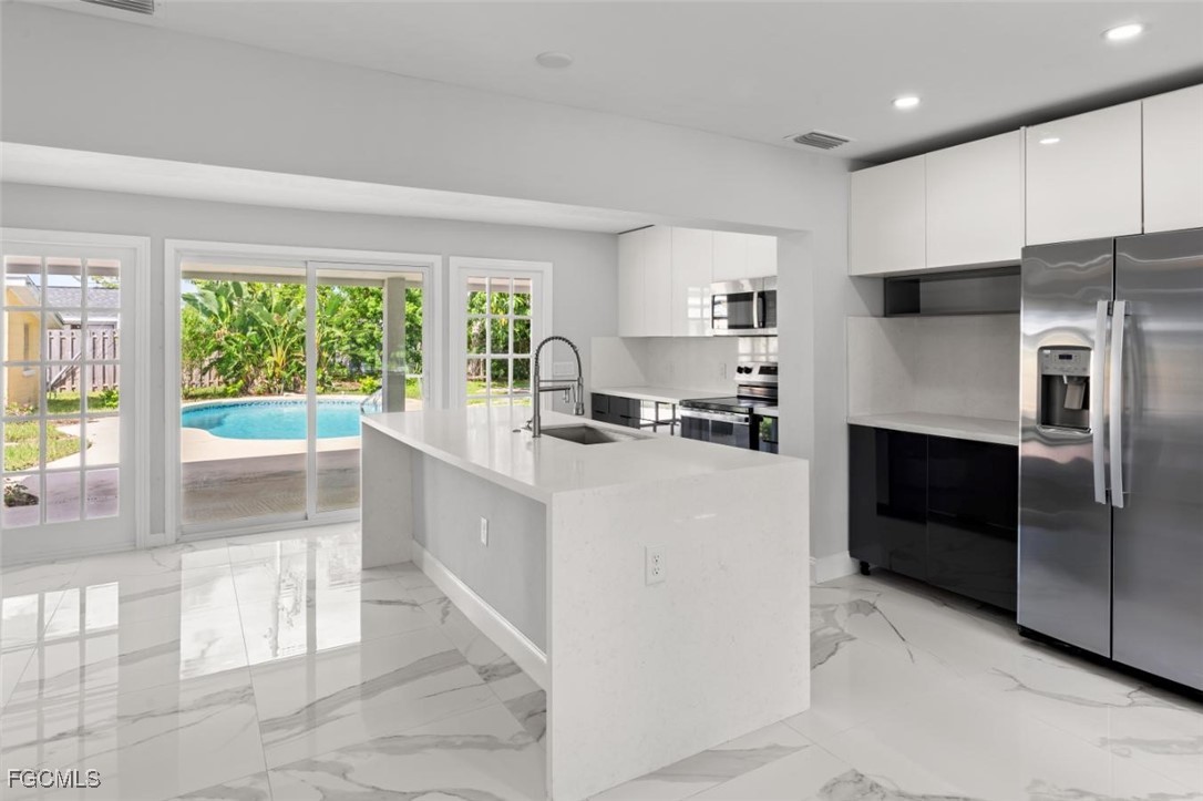 4970 Riverside Drive Estero, FL 33928 - Photo 11 of 35 a kitchen with stainless steel appliances a refrigerator sink and cabinets