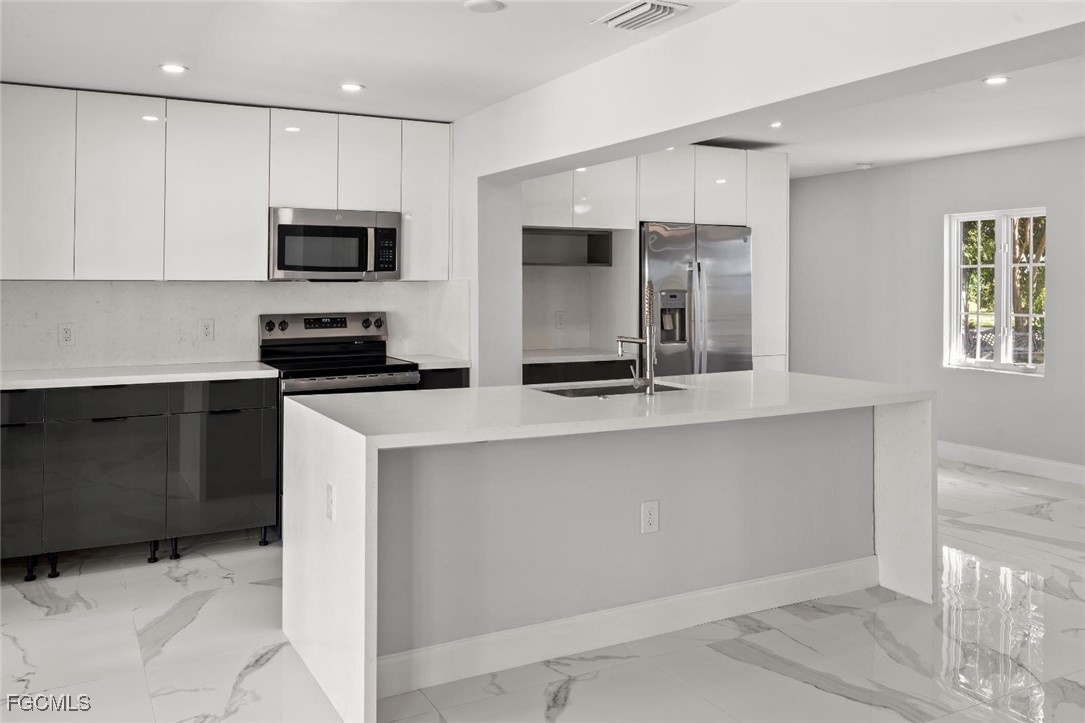 4970 Riverside Drive Estero, FL 33928 - Photo 18 of 35 a kitchen with stainless steel appliances a stove microwave and sink