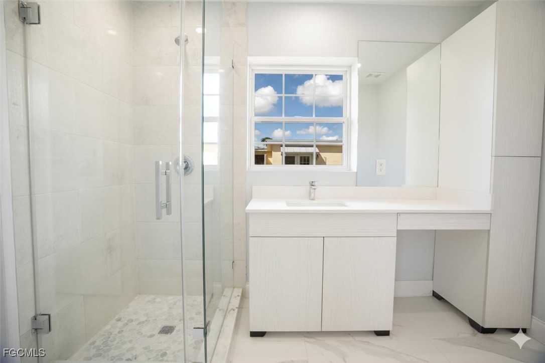 4970 Riverside Drive Estero, FL 33928 - Photo 23 of 35 a bathroom with a sink a mirror and a shower
