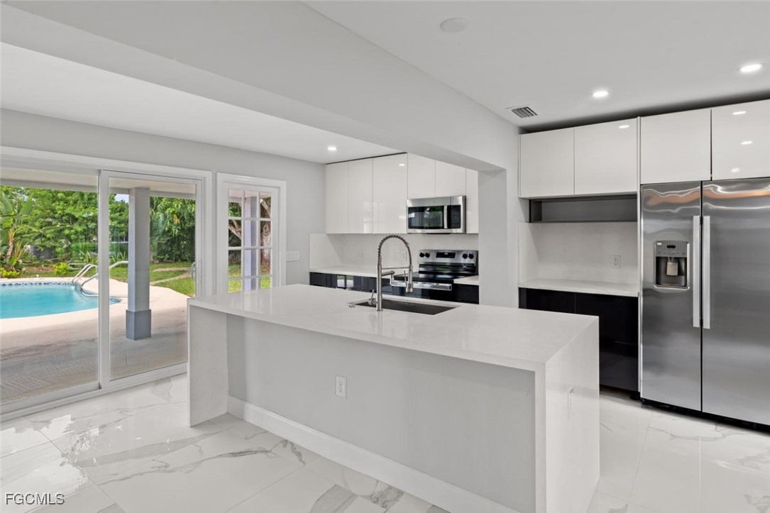 4970 Riverside Drive Estero, FL 33928 - Photo 10 of 35 a kitchen with kitchen island a large counter top space a sink stainless steel appliances and cabinets