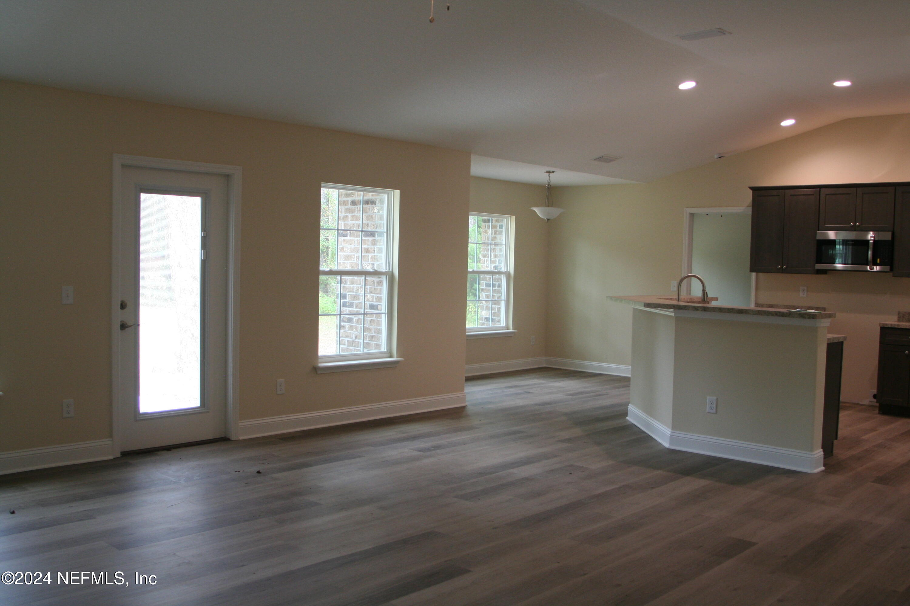 54835 Dornbush Road Callahan, FL 32011 - Photo 13 of 31 a view of a kitchen and an empty room with wooden floor and a window