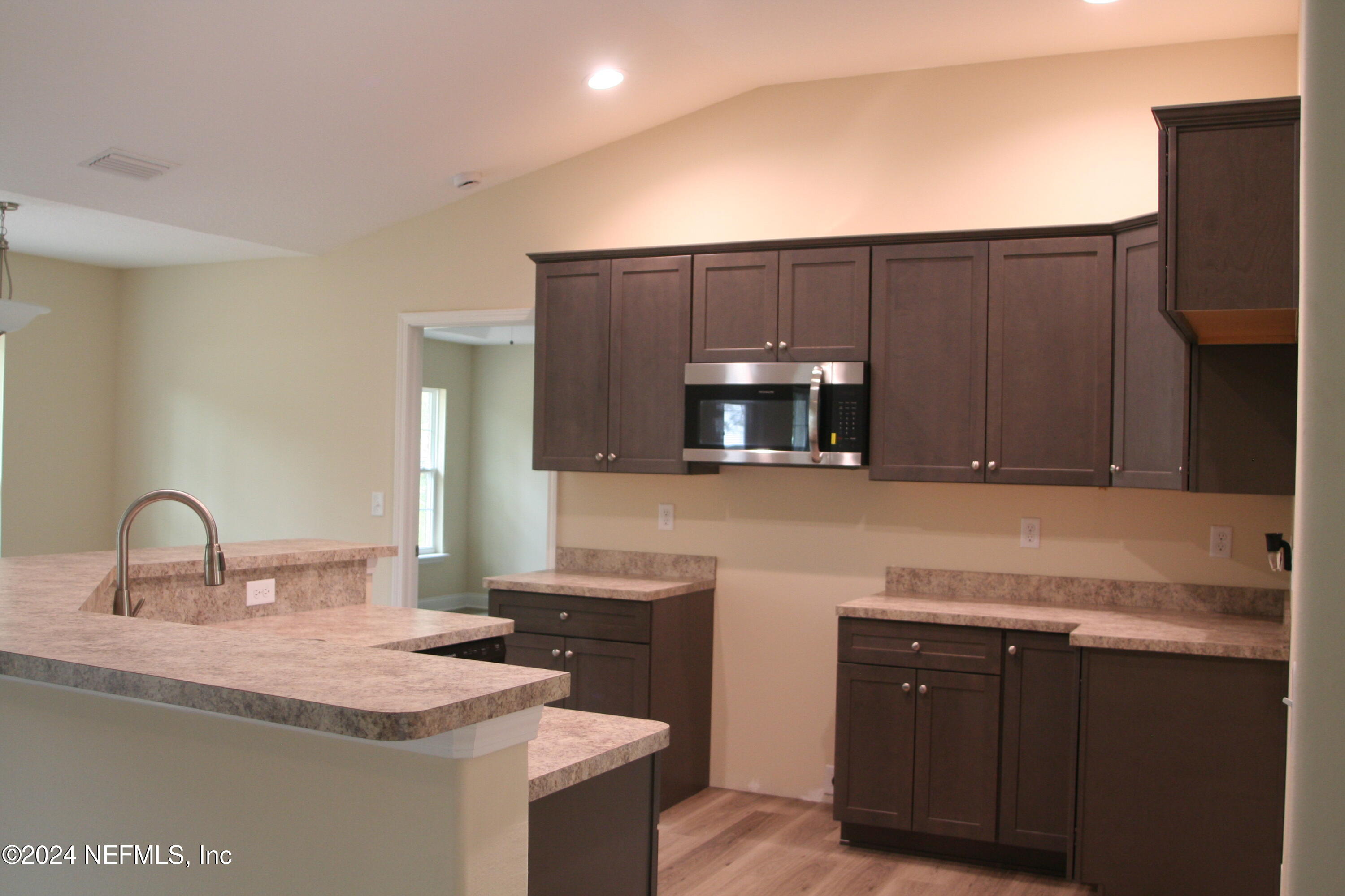 54835 Dornbush Road Callahan, FL 32011 - Photo 17 of 31 a kitchen with stainless steel appliances granite countertop a sink stove and microwave