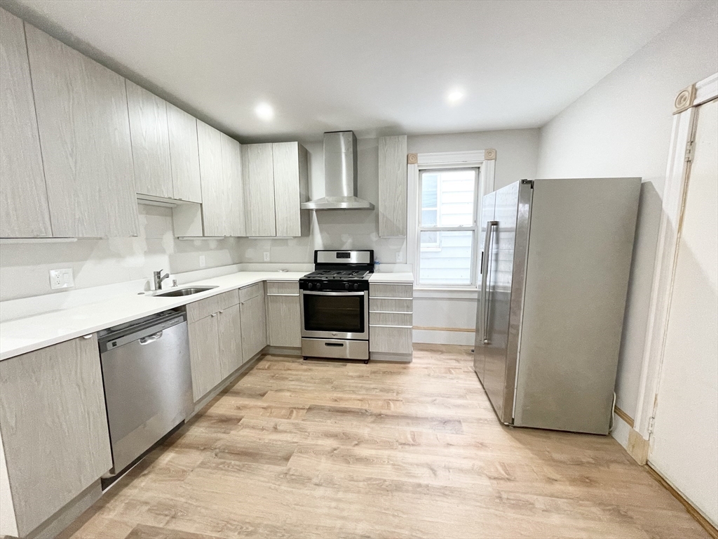 10 Wave Avenue, Unit 2 Boston, MA 02125 - Photo 3 of 15 a kitchen with a refrigerator a stove top oven and cabinets