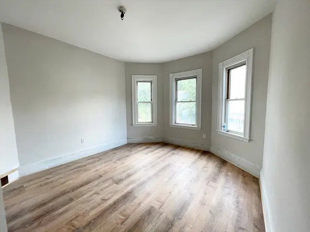 a view of an empty room with wooden floor and window