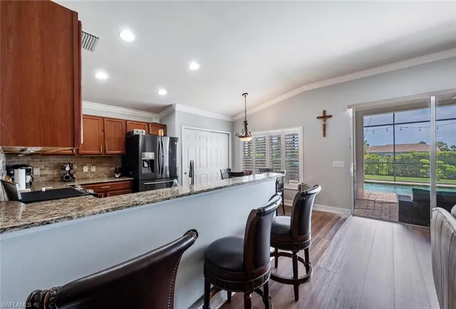 a dining hall with stainless steel appliances granite countertop a stove top oven a sink dishwasher a dining table and chairs with wooden floor