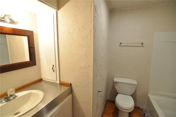 a bathroom with a granite countertop toilet sink and mirror