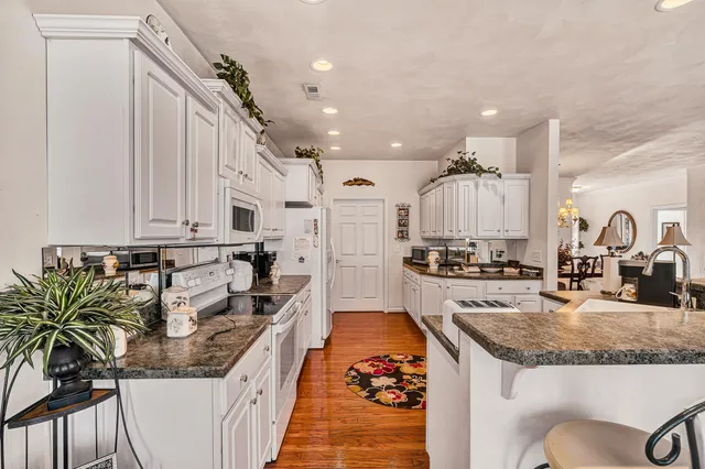 a kitchen with granite countertop a sink a stove and a refrigerator