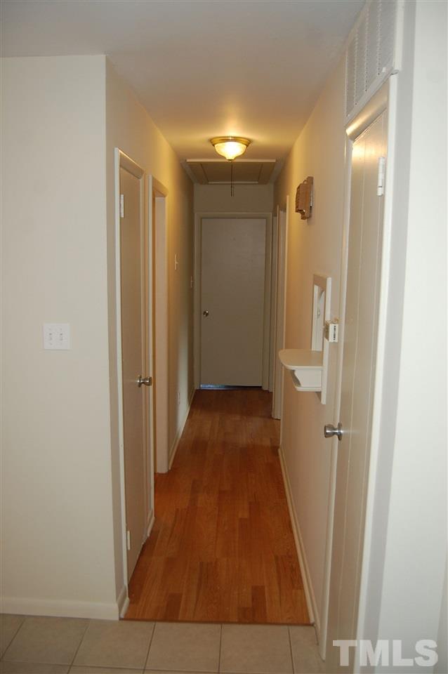 1009 Somerset Road Raleigh, NC 27610 - Photo 5 of 13 a view of a hallway with wooden floor and a bathroom
