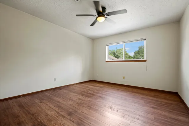 an empty room with wooden floor fan and windows