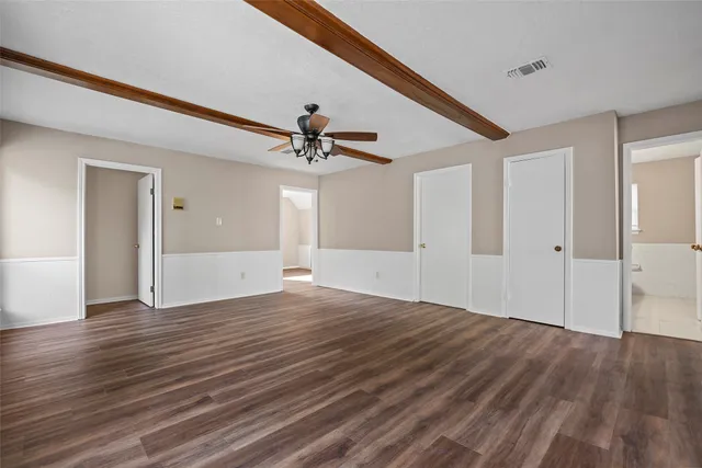 a view of empty room with wooden floor and ceiling fan