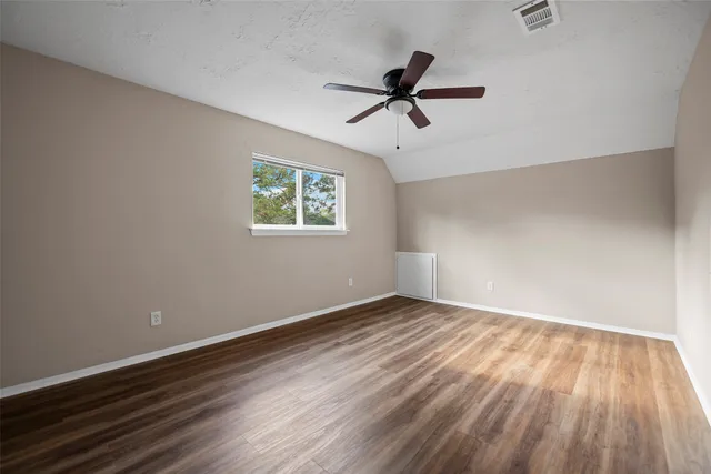 a view of empty room with wooden floor and fan