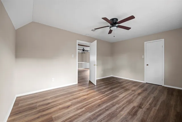 a view of empty room with wooden floor and ceiling fan