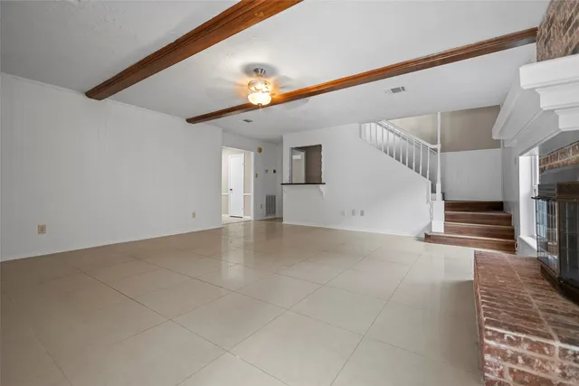 a view of an empty room with stairs and a ceiling fan