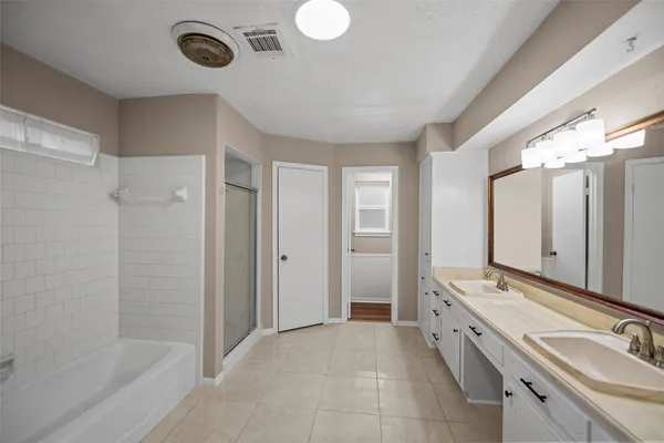 a spacious bathroom with a double vanity sink a mirror and a bathtub