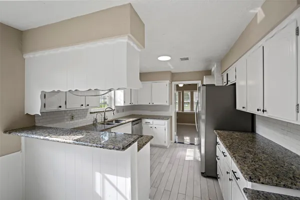 a kitchen with granite countertop a refrigerator stove oven and wooden floor