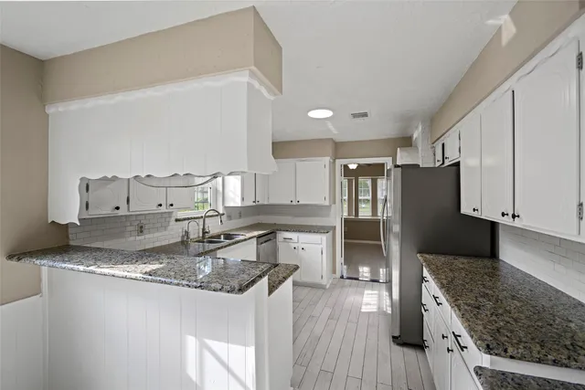 a kitchen with granite countertop a refrigerator stove oven and wooden floor