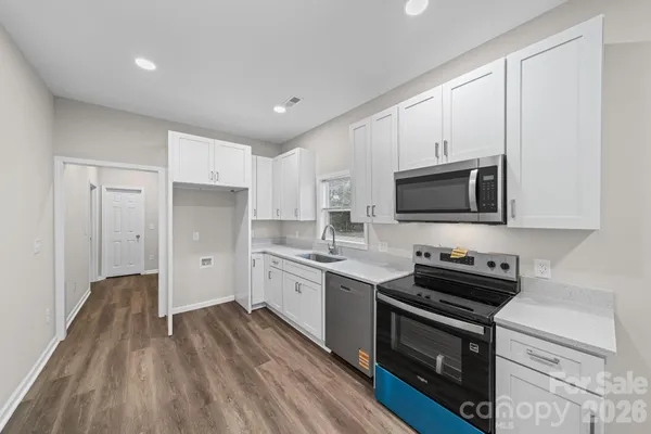 a kitchen with stainless steel appliances a sink dishwasher a stove and a microwave oven on granite countertops