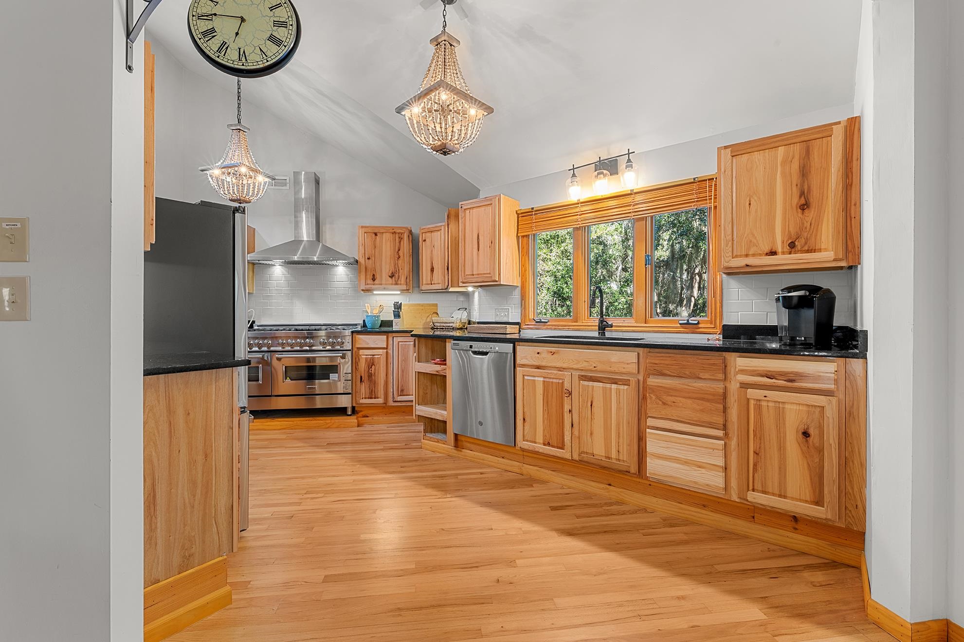187 Alston Road Pawleys Island, SC 29585 - Photo 20 of 40 Kitchen with decorative light fixtures, light wood-style flooring, wall chimney exhaust hood, appliances with stainless steel finishes, and lofted ceiling