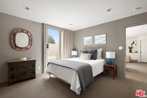 a bedroom with a bed a dresser and a potted plant