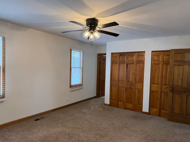 an empty room with closet and a chandelier fan