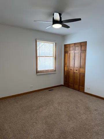 an empty room with chandelier fan and windows