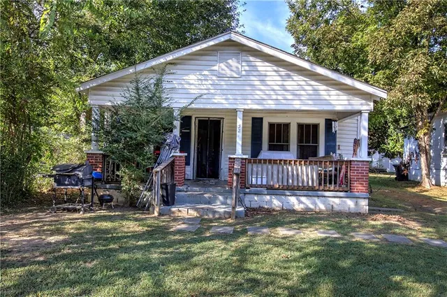 a view of a house with a small yard and a large tree