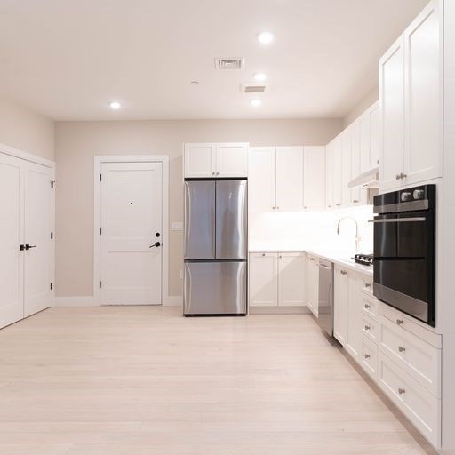 197 Green Street, Unit 202 Boston, MA 02130 - Photo 2 of 8 a kitchen with granite countertop white cabinets and stainless steel appliances