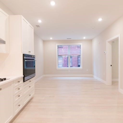 197 Green Street, Unit 202 Boston, MA 02130 - Photo 4 of 8 an empty room with windows and cabinet