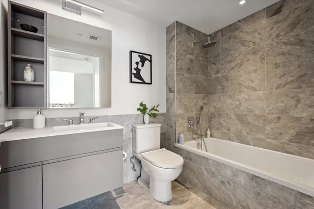 a bathroom with a granite countertop sink toilet a mirror and bathtub