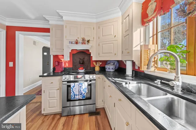 a kitchen with stainless steel appliances granite countertop a sink and a stove next to a window