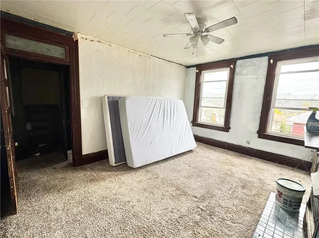 an empty room with windows and fan