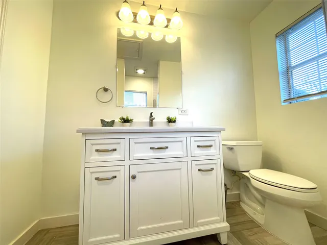 a bathroom with a sink vanity mirror and toilet